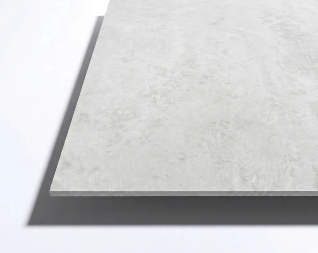 A rectangular, light gray ceramic or stone tile with a subtle textured surface, photographed from an angle showing thickness and shadow.