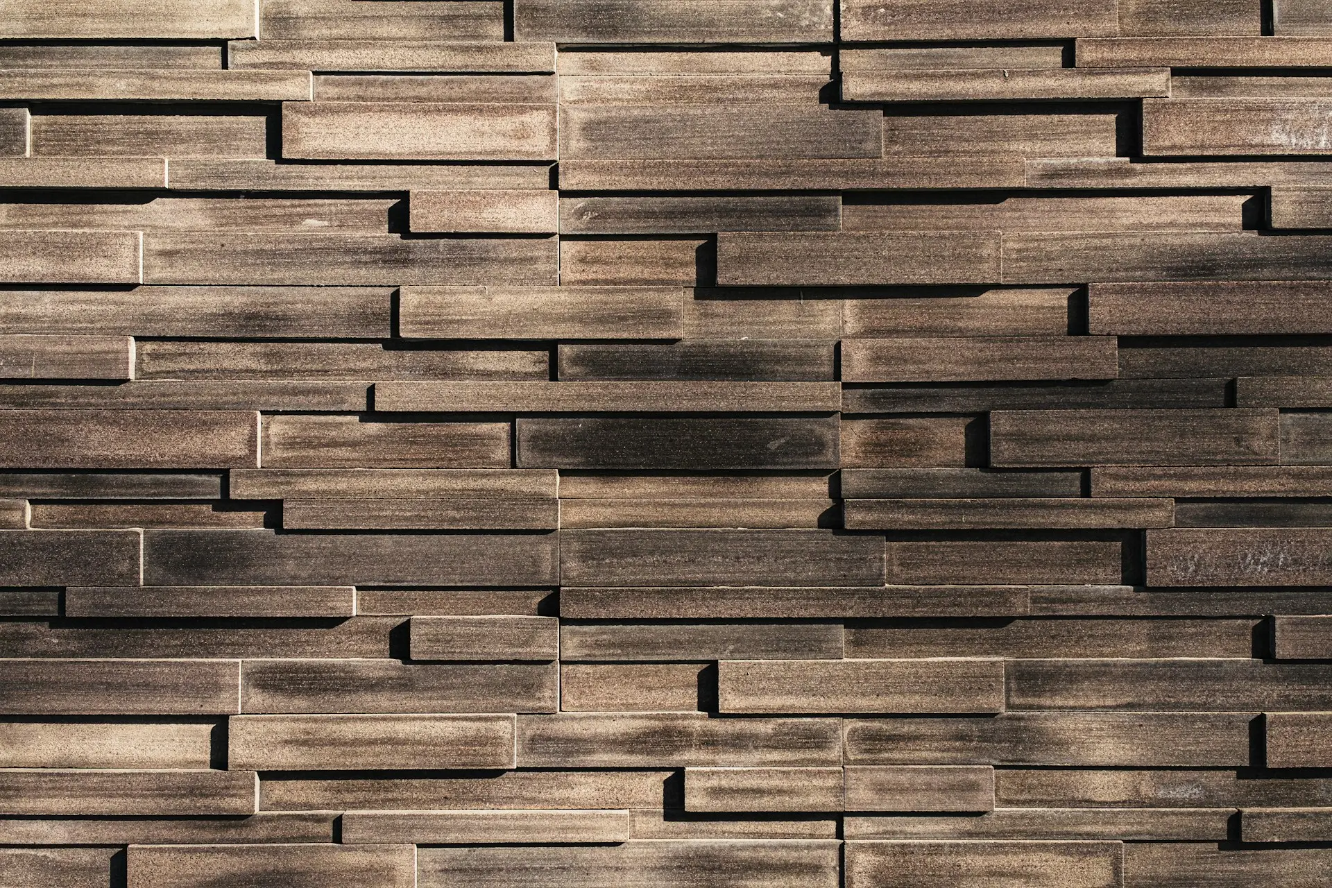 Rectangular wooden planks arranged in a staggered, overlapping pattern, creating a textured geometric wall.
